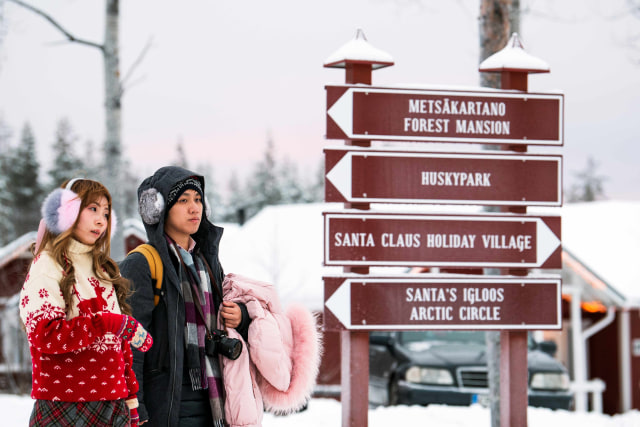 Pengunjung melihat papan informasi di Desa Sinterklas, Rovaniemi, Lapland, Finlandia. Foto: Jonathan NACKSTRAND / AFP