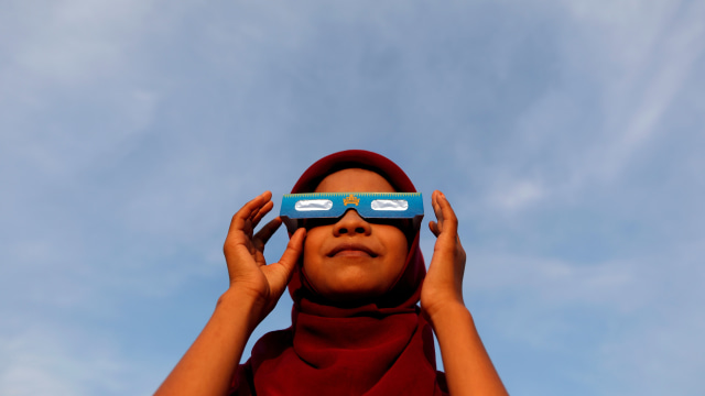 Seorang anak mencoba kacamata untuk melihat gerhana matahari di Kabupaten Siak, provinsi Riau, Rabu (25/12). Foto: REUTERS/Willy Kurniawan