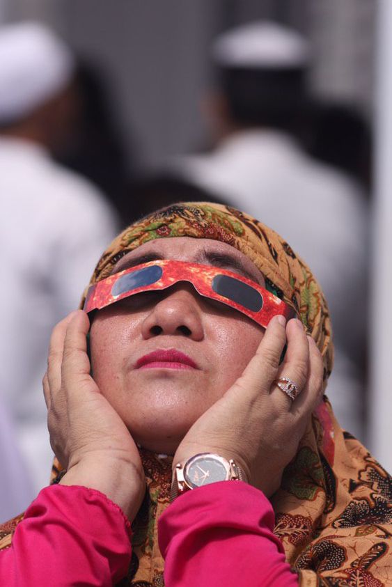 Seorang warga menyaksikan gerhana matahari cincin menggunakan kacamata. Foto: Windy Phagta/acehkini