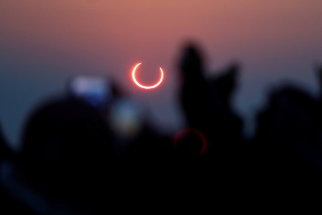 Warga mengambil foto proses terjadinya gerhana matahari cincin di Hofuf, Arab Saudi.  Foto: REUTERS / Hamad I Mohammed