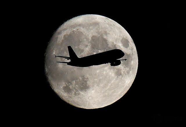 Sebuah pesawat lewat di depan bulan saat melakukan pendaratan di Bandara Heathrow, London, Ingris pada 12 September 2019. Foto: REUTERS/Toby Melville