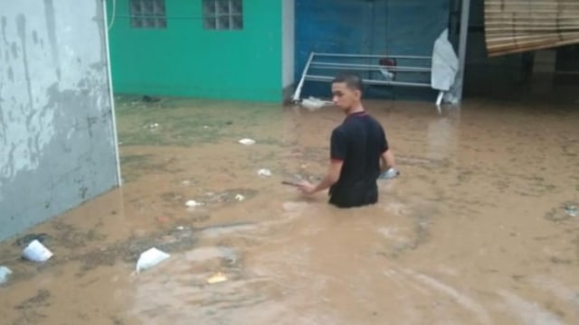 Seorang warga Cimareme Kabupaten Bandung Barat terlihat berjalan melintasi banjir, Selasa (31/12). (Foto: dok. BPBD Jabar)