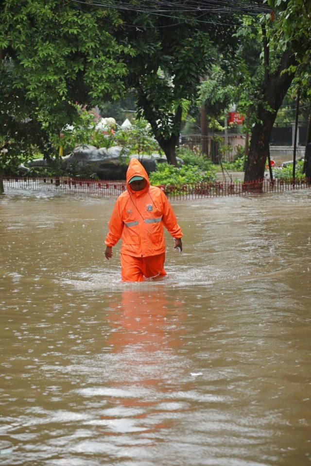 Petugas kebersihan melintasi banjir di Kemang Timur, Jakarta Selatan, Rabu (1/1/2020). Foto: Fanny Kusumawardhani/kumparan