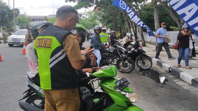 PETUGAS Yustisi dari Badan Pendapatan Daerah Provinsi Riau memeriksa kelengkapan surat-surat pengendara motor dalam sebuah razia.  