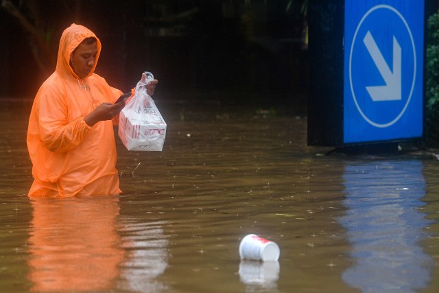 Kurir pengantar makanan melintasi Jalan Kemang Raya yang terendam banjir Jakarta Selatan, Rabu (1/1). Foto: ANTARA FOTO/Sigid Kurniawan