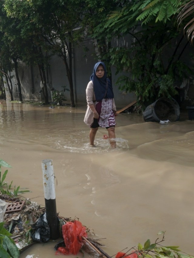 Seorang warga melewati genangan banjir di Pondok Mitra Lestari (PML) Bekasi. Foto: Iqbal Firdaus/kumparan