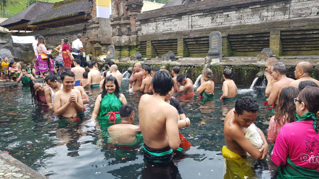 Beberapa wisatawan asing dan lokal serta umat Hindu membersihkan diri di tempat pemandian suci yang terdapat di Pura Tirtha Empul | Photo by Charles/Karja