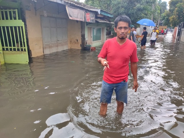 Warga Pulo Indah, Izal (40), saat menemukan ikan koi di area banjir, Jumat (3/1). Foto: Abyan Faisal Putratama