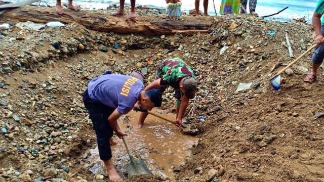 Aparat TNI dan Polri bersama warga menggali tanah untuk menguburkan bangkai ika paus. Sabtu, (4/1) Foto : Istimewa  