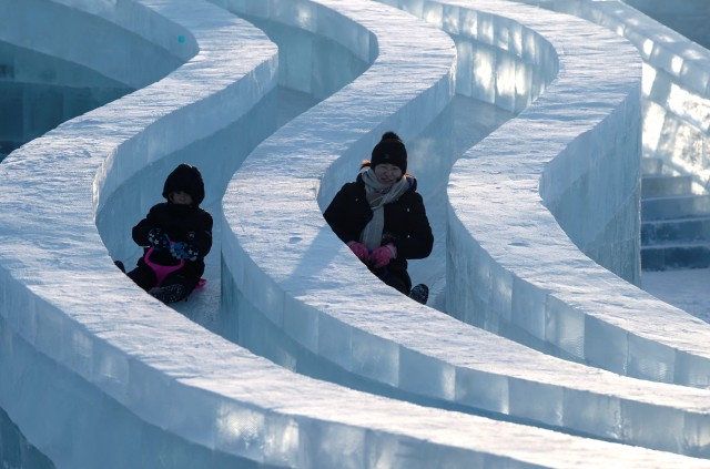 Pengunjung meluncur di atas patung es di Festival Dunia Es dan Salju Harbin 2020 di Harbin, China. Foto: AFP/NOEL CELIS 