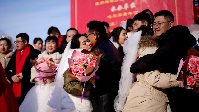 Pasangan pengantin baru menghadiri upacara pernikahan massal pada festival es tahunan di kota utara Harbin, provinsi Heilongjiang, China, Minggu (5/1). Foto: REUTERS/Aly Song