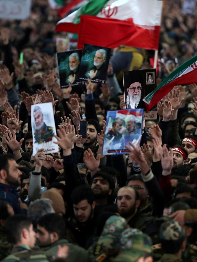 Masyarakat membawa poster Qassem Soleimani dan bendera Iran.
 Foto: Official Khamenei website/Handout via REUTERS
