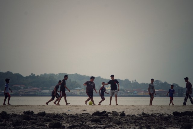 Para remaja sedang bermain sepak bola kala air laut surut dikawasan tepi laut Tanjungpinang dengan latar belakang Pulau Penyengat. Foto : Ismail/kepripedia.com