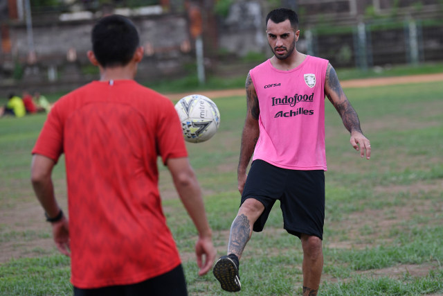 Pesepak bola Bali United Brwa Nouri (kanan) menendang bola ke rekannya Dias Angga Putra saat latihan ketahanan fisik di GOR Ngurah Rai, Denpasar, Bali. Foto: ANTARA FOTO/Nyoman Budhiana