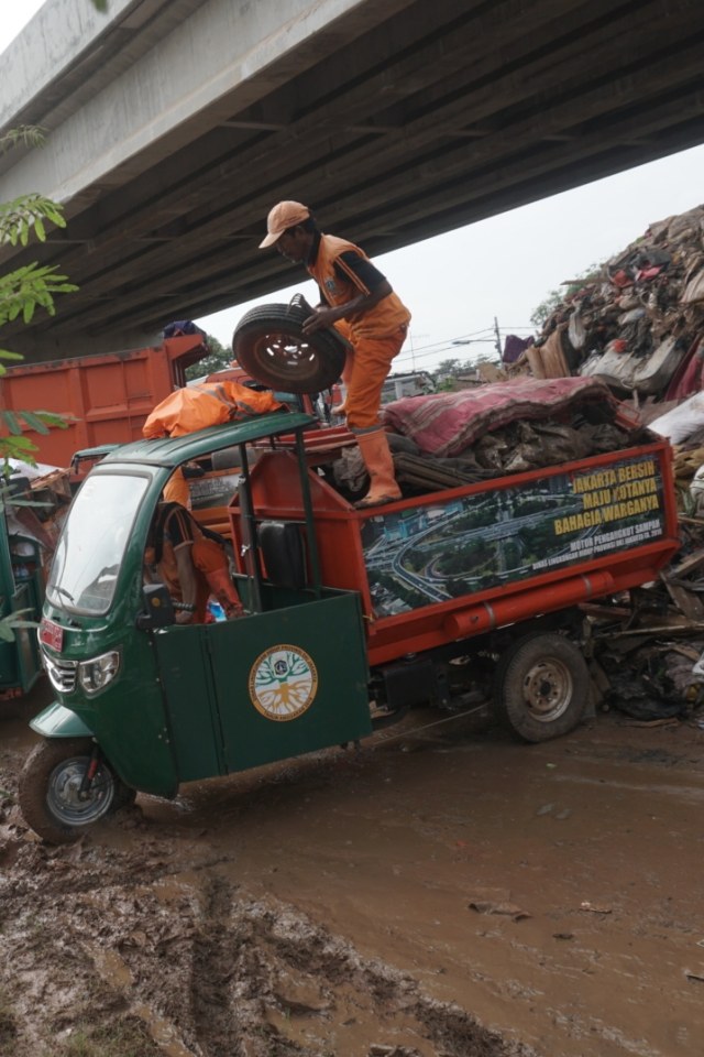 Petugas PPSU mengangkut sampah sisa banjir yang menumpuk di kolong tol Becakayu, Jakarta, Kamis (9/1). Foto: Iqbal Firdaus/kumparan
