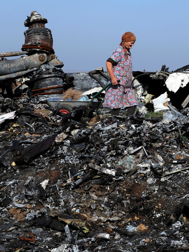 Seorang warga melewati puing Malaysia Airlines flight MH17 yang jatuh tahun 2014 di Ukraina. Foto: AFP/DOMINIQUE FAGET