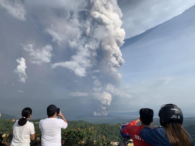 Sejumlah orang memotret gunung berapi Taal yang meletus yang terlihat dari Kota Tagaytay, Filipina, Minggu (12/1/2020). Foto: AFP/Bullit MARQUEZ