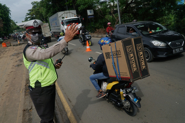 Polisi mengatur lalu lintas di sekitar jalan yang amblas di Daan Mogot, Tangerang, Senin (14/1/2020). Foto: Jamal Ramadhan/kumparan
