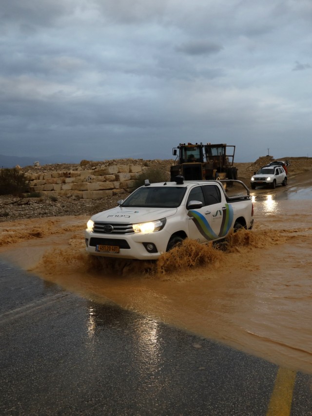 Kendaraan melintas aliran air banjir mengalir melintasi jalan dekat Kibutz Ein Gegi di gurun Yudea, Israel.  Foto: AFP/MENAHEM KAHANA