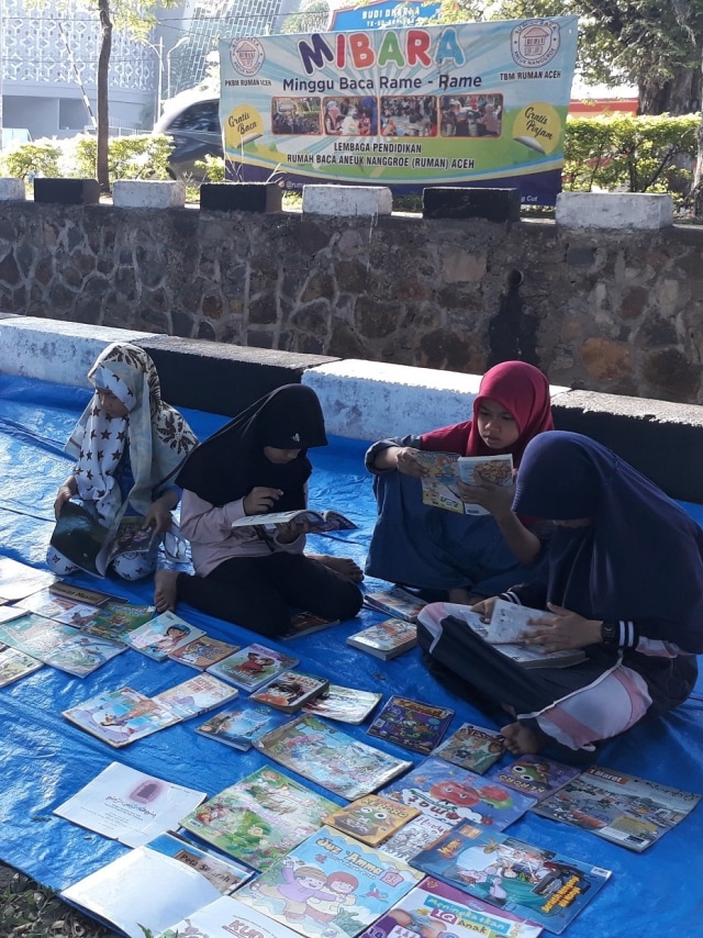 Anak-anak membaca buku yang disediakan RUMAN Aceh setiap hari Minggu di lapangan Blang Padang, Banda Aceh. Dok. RUMAN Aceh