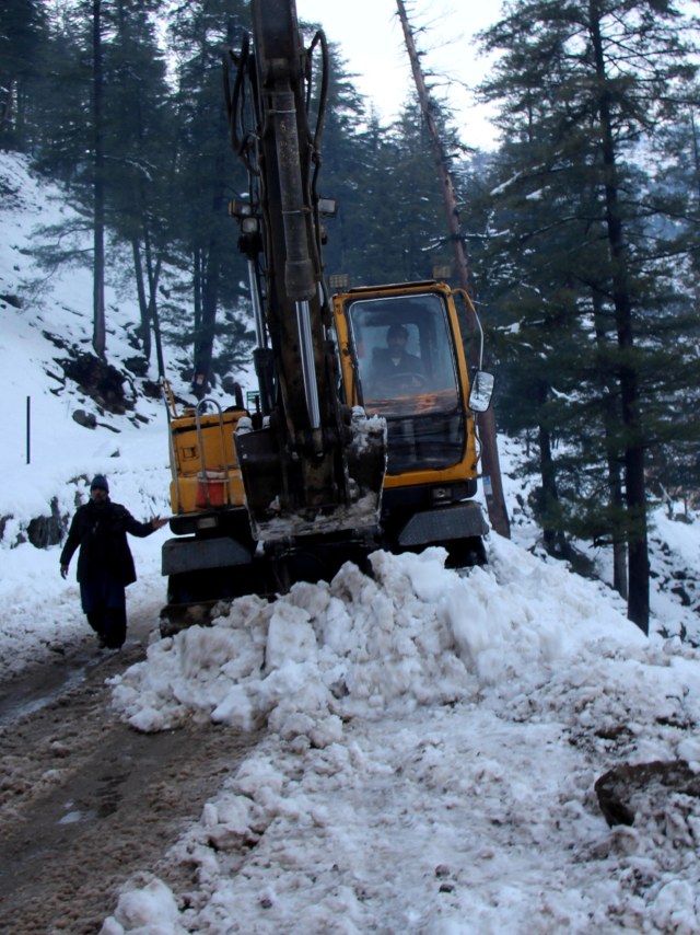 Ekskavator memindahkan batu-batu salju di jalan setelah hujan salju lebat di Lembah Neelum, Pakistan. Foto: REUTERS/Naseer Chaudary 