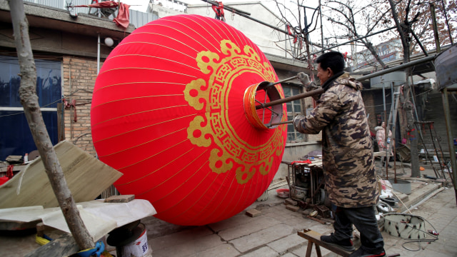 Penduduk lokal Bai Junping membuat lampion tradisional raksasa menjelang perayaan Tahun Baru Imlek Cina di desa Tuntoucun, di Shijiazhuang, China. Foto: REUTERS/Jason Lee