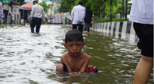 Seorang anak yang terlihat sedang duduk menikmati suasana banjir di Jalan Dr. Sutomo, Samarinda | Photo by Karja/Risky