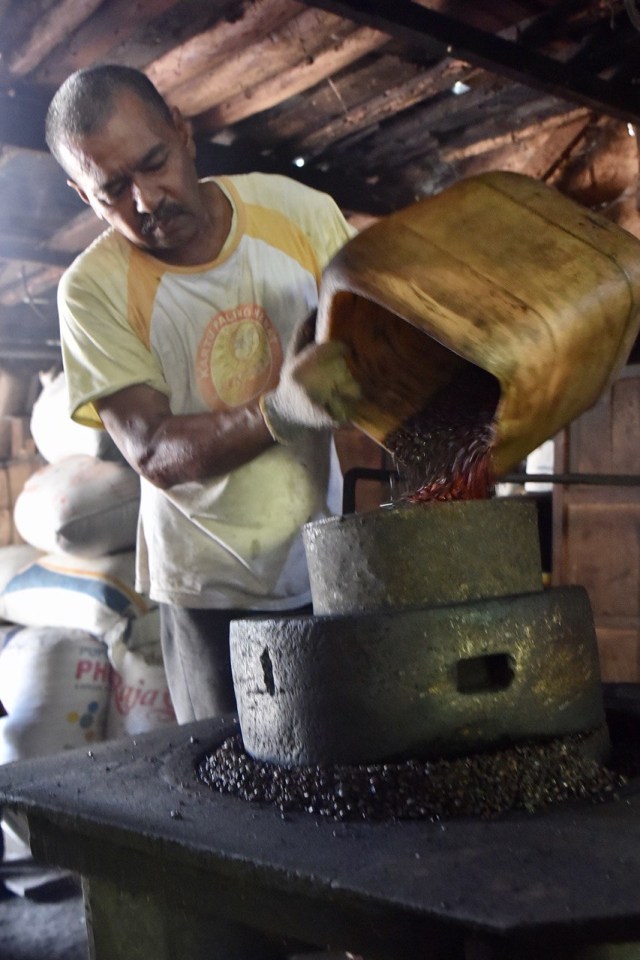 Azhar dan gilingan kopi tradisional berusia 100 tahun lebih. Foto: Reza Juanda/acehkini