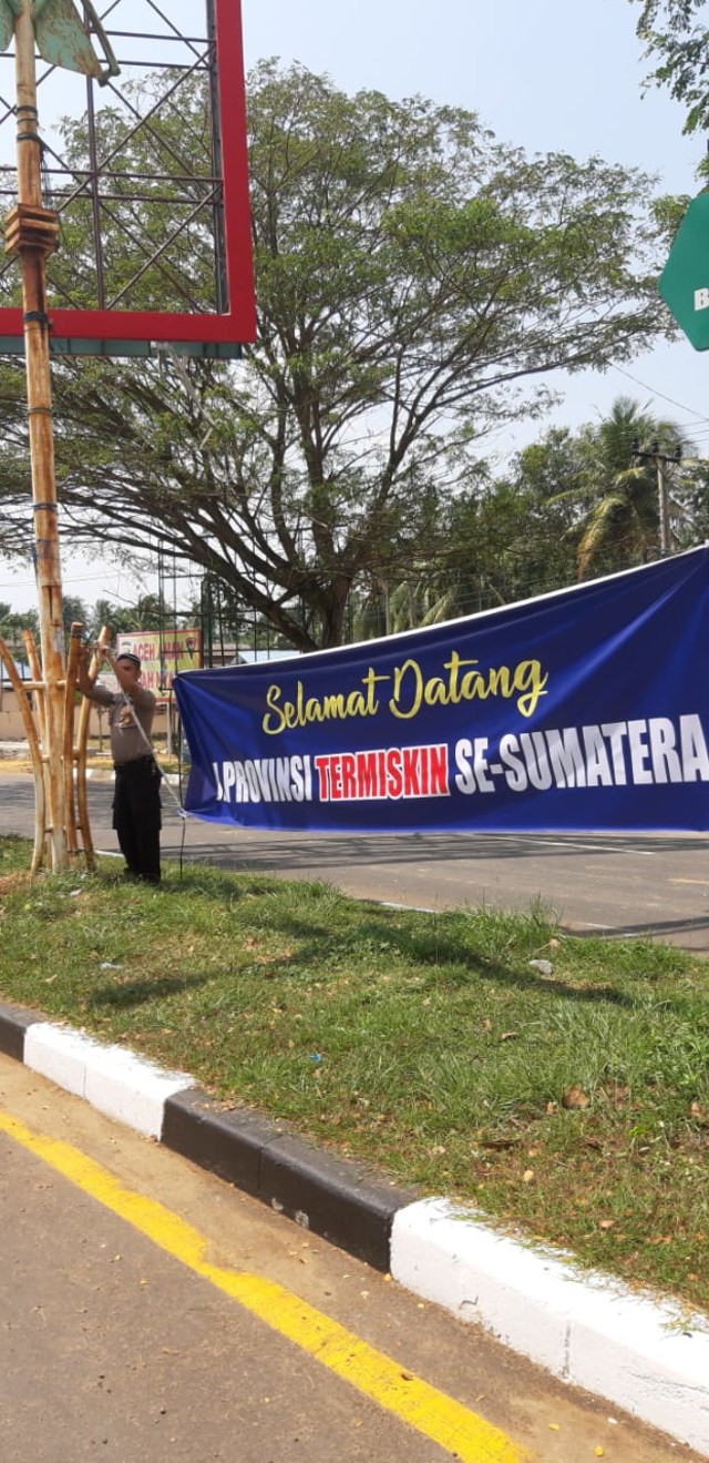Personel kepolisian mencopot spanduk ucapan selamat Aceh termiskin di Sumatera yang terpasang di pinggir jalan. Foto: Dok. Polresta Banda Aceh