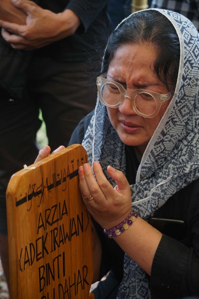 Dewi Irawan berdoa di makam Ade Irawan. Foto: Irfan Adi Saputra/kumparan