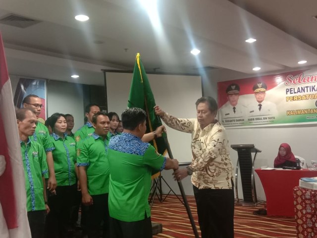 Plt Ketua Umum Perpani Pusat H. Sony Haryanto saat menyerahkan bendera Perpani kepada Ketua Pengprov Perpani Kalteng Ade Surpyadi dalam pelantikan pengurus Pengprov Perpani Kalteng, Minggu (19/01) di Hotel Neo, Palangka Raya.