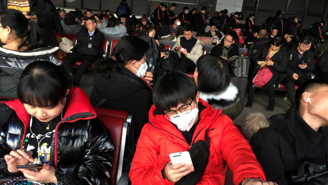 Seorang wanita mengenakan masker di ruang tunggu di Stasiun Kereta Api Barat Beijing. Foto: REUTERS/Stringer