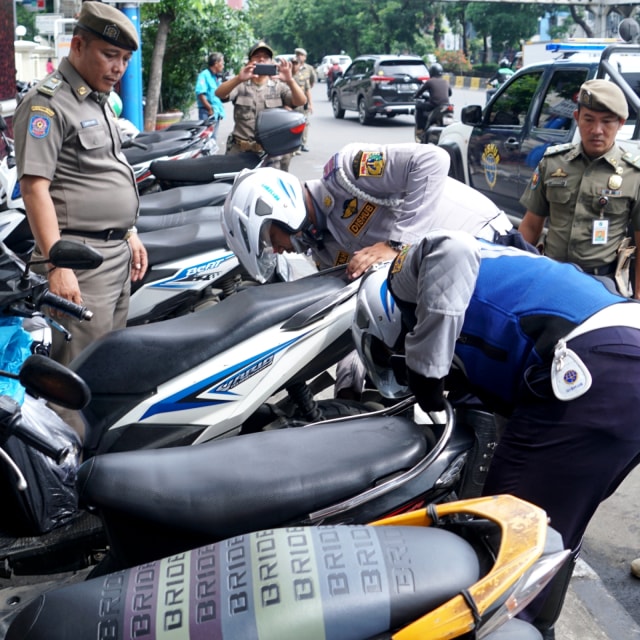Petugas Dinas Perhubungan DKI Jakarta mencabut pentil ban motor yang parkir liar di kawasan Gajah Mada, Jakarta, Selasa (21/1/2020). Foto: Helmi Afandi/kumparan