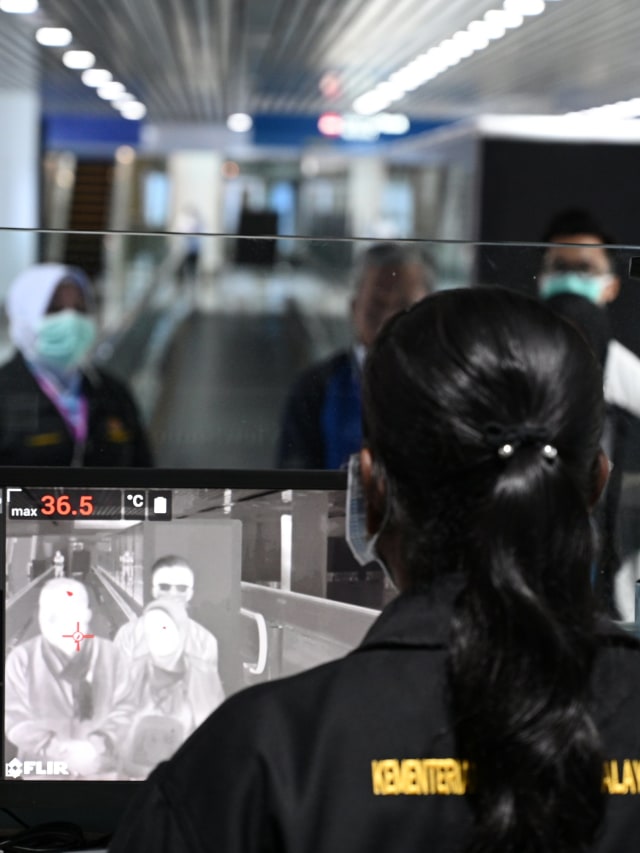 Petugas kesehatan Malaysia menggunakan 'thermal scanner' mendeteksi suhu tubuh penumpang yang tiba di Bandara Internasional Kuala Lumpur, Malaysia. Foto: AFP/MOHD RASFAN 