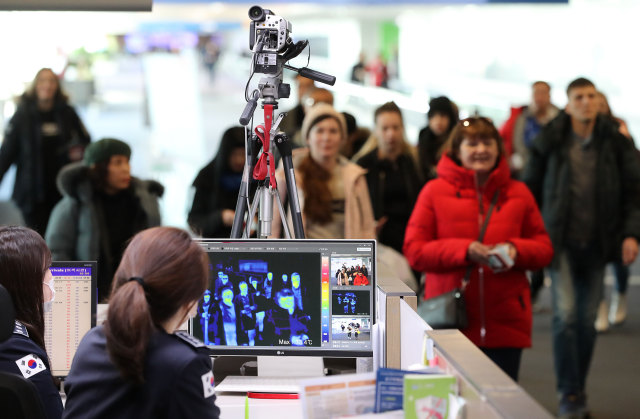 Petugas menggunakan 'thermal scanner' mendeteksi suhu tubuh penumpang yang tiba di Bandara Internasional Incheon, Korea Selatan. Foto: AFP/STR