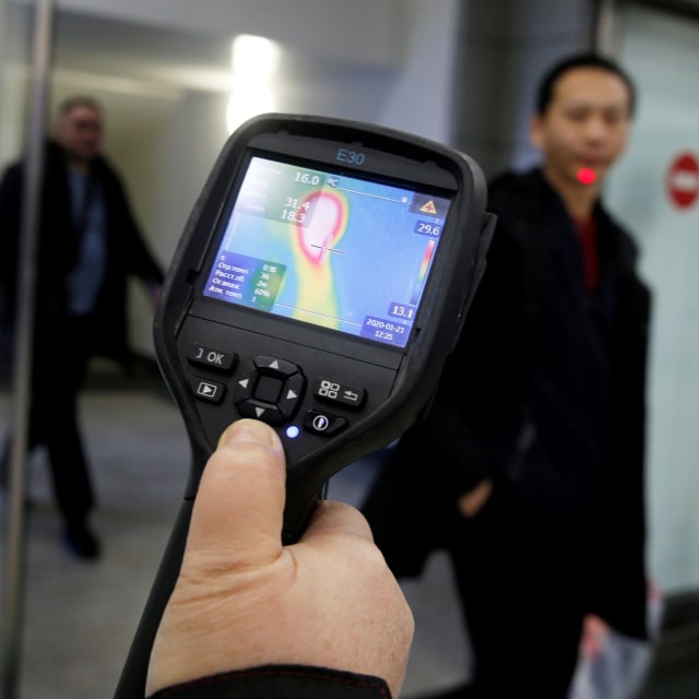 Petugas kesehatan menggunakan 'thermal scanner' mendeteksi suhu tubuh penumpang yang tiba di Bandara Internasional Almaty, Kazakhstan. Foto: REUTERS / Pavel Mikheyev