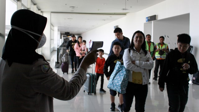 Petugas melakukan pendeteksi suhu tubuh (thermal scanner) saat penumpang pesawat tiba di terminal 2 Bandara Juanda Surabaya, Jawa Timur, Rabu (22/1). Foto: ANTARA FOTO/Umarul Faruq