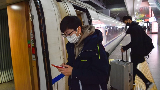 Penumpang mengenakan masker memasuki di kereta untuk menuju Kota Wuhan di stasiun kereta Hongqioa, China. Foto: AFP/HECTOR RETAMAL