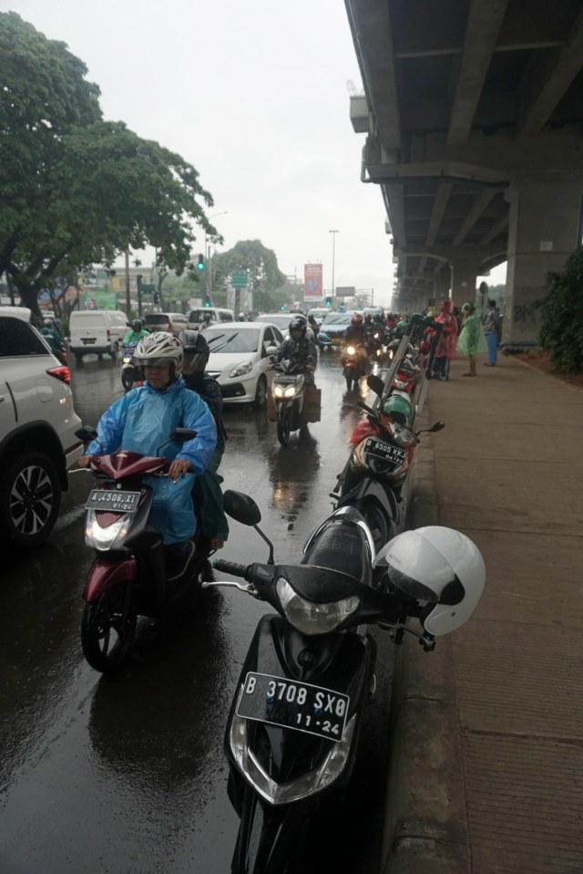 Pemotor memarkirkan kendaraan di pinggir jalan saat berteduh di bawah jalan layang saat hujan deras. Foto: Iqbal Firdaus/kumparan