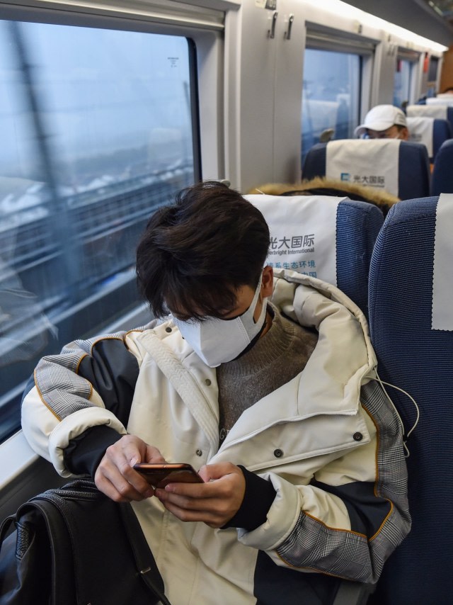 Penumpang mengenakan masker duduk di kereta untuk menuju Kota Wuhan di stasiun kereta Hongqioa, China. Foto: AFP/HECTOR RETAMAL