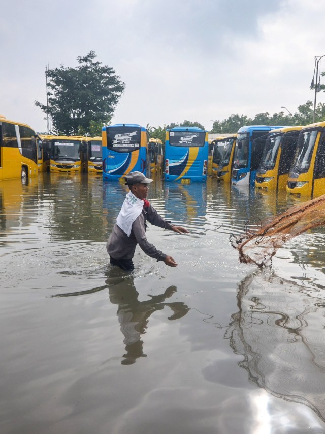 Seorang warga mencari ikan diantara bus sekolah dan Trans Metro Bandung (TMB) yang terendam banjir di Balai Pengujian Kendaraan Dinas Perhubungan, Bandung. Foto: ANTARA FOTO/Raisan Al Farisi