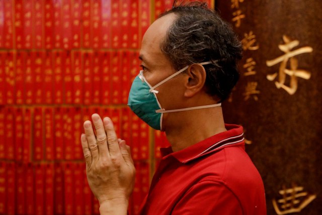 Seorang pria yang mengenakan masker berdoa saat perayaan Tahun Baru Imlek. Foto: REUTERS/Eloisa Lopez