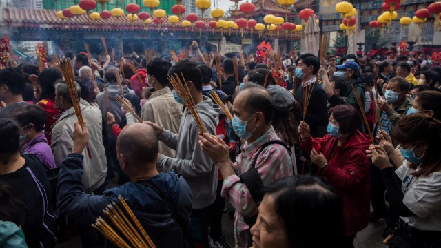 Orang-orang memakai masker saat mereka mengunjungi kuil Wong Tai Sin pada hari pertama Tahun Baru Imlek Tikus di Hong Kong, Sabtu (25/1). Foto: DALE DE LA REY / AFP