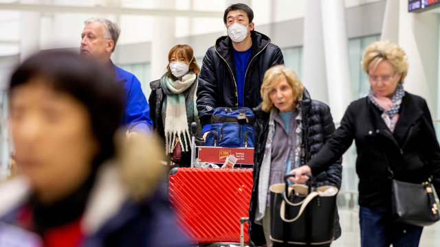 Wisatawan menggunakan masker berdatangan di Bandara Pearson, Torontom Ontario, Kanada. Foto: REUTERS / Carlos Osorio