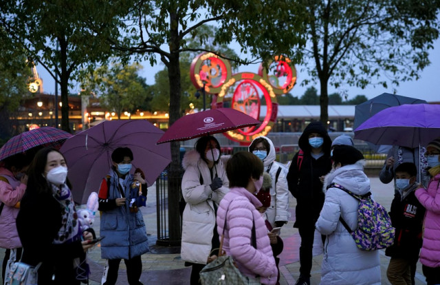 Pengunjung mengenakan masker berjalan keluar dari resor Disney, Shanghai | Photo by ALY SONG/Reuters 