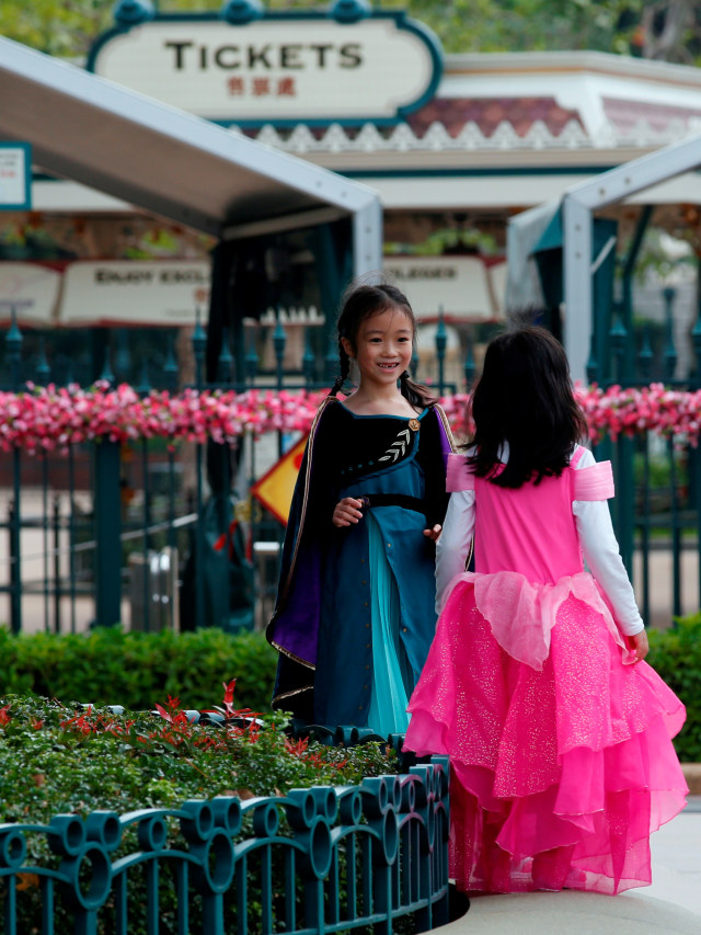 Anak-anak bermain di luar Disneyland, Hong Kong yang ditutup akibat virus corona, Minggu (26/1). Foto: REUTERS/Tyrone Siu