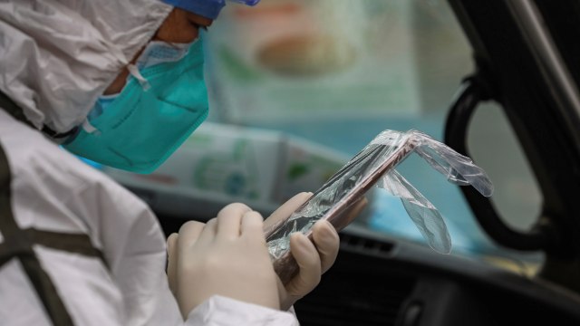 Petugas medis menggunakan handphone yang terbungkus plastik. Foto: Chinatopix via AP