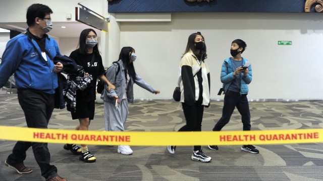 Sejumlah penumpang berjalan di area pemindaian suhu tubuh di Terminal Kedatangan Internasional Bandara Internasional I Gusti Ngurah Rai, Bali, Minggu (26/1). Foto: ANTARA FOTO/Fikri Yusuf