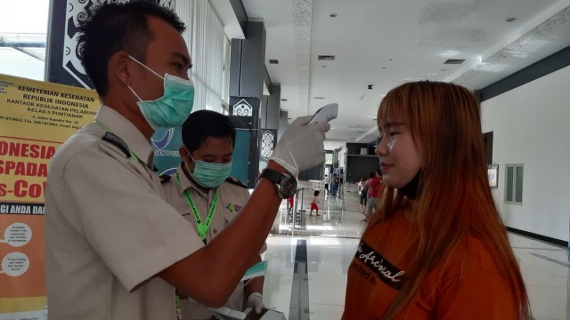 Petugas memeriksa warga yang tiba di PLBN Entikong, Senin (27/1). Foto: Dok. A. Alfian