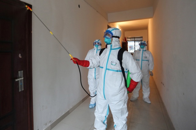Petugas mengenakan pakaian pelindung mendisinfeksi area perumahan di Ruichang di sebelah provinsi Hubei. Foto: STR / AFP